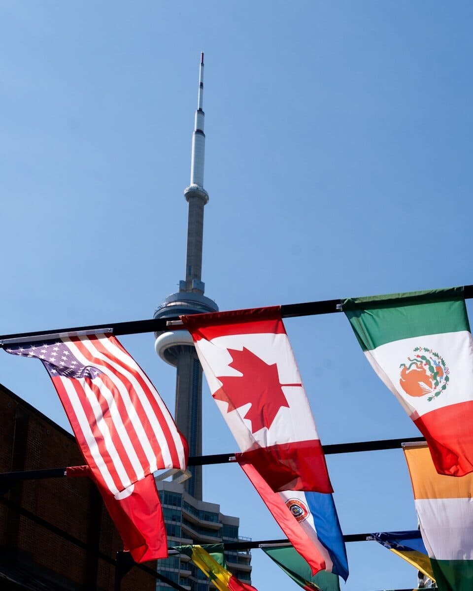 National flags hang with the cn tower in background.